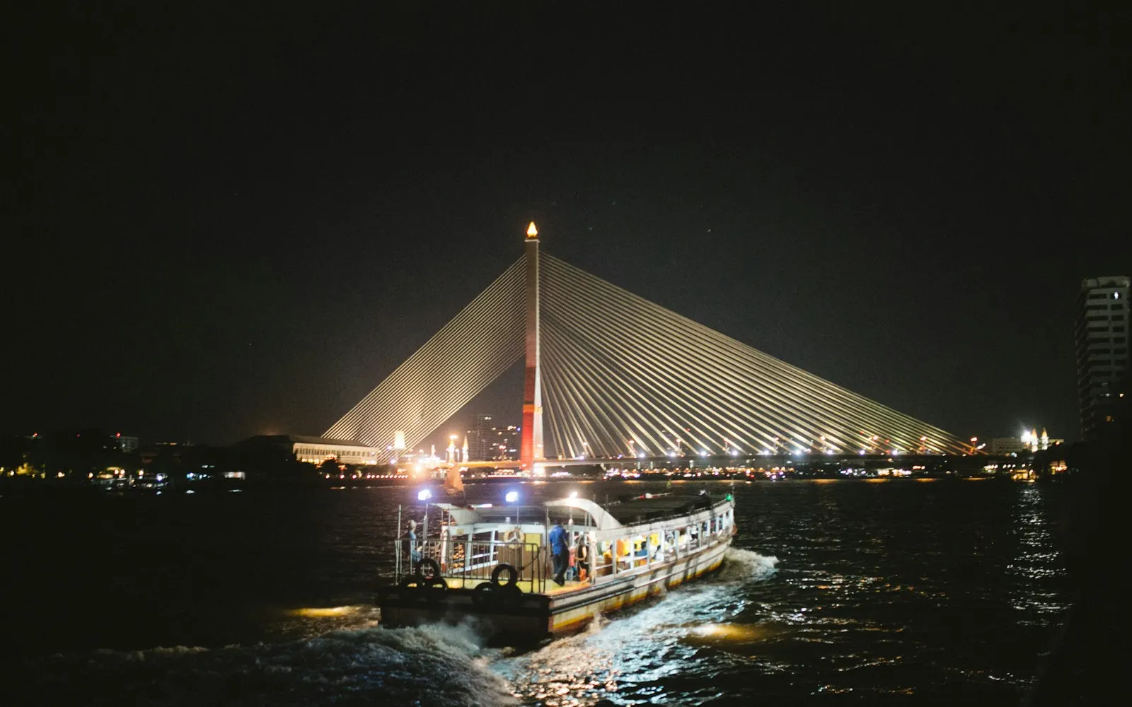 Illuminated passenger boat travelling on a city river at night